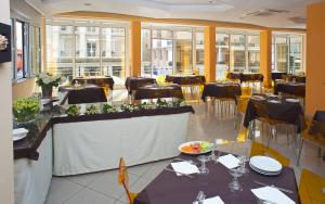 een eetkamer met tafels, stoelen en ramen bij Hotel Austria in Rimini