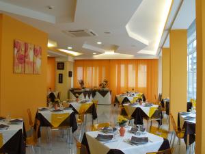 a dining room with tables and chairs and a room with yellow walls at Hotel Austria in Rimini