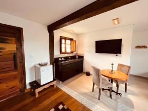 a living room with a table and a television at Sonho Real Suítes in Lavras Novas