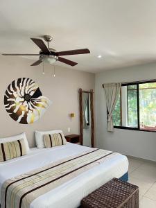 1 dormitorio con 1 cama y ventilador de techo en Maya Eco Village, en Akumal