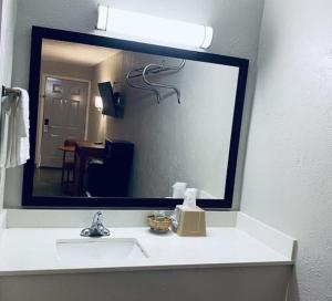 lavabo en el baño con un espejo grande encima. en Executive Inn en Kingsville