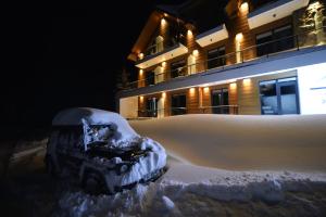 Ein Auto, das vor einem Haus im Schnee begraben ist in der Unterkunft Alliance Villa Gоderdzi in Khulo