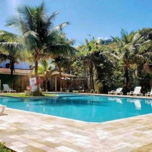 una gran piscina con palmeras y sillas en Casa de praia em condomínio fechado Juquei, en São Sebastião