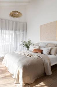a white bedroom with a large bed with pillows at Currumbin Sanctuary Beach Abode in Gold Coast