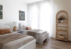 a white bedroom with two beds and a window at Currumbin Sanctuary Beach Abode in Gold Coast