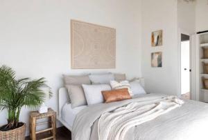 a white bedroom with a bed and a plant at Currumbin Sanctuary Beach Abode in Gold Coast