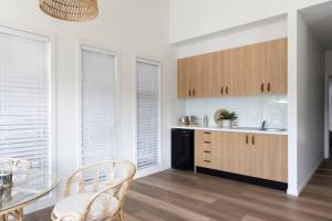 a kitchen with wooden cabinets and a table and chairs at Currumbin Sanctuary Beach Abode in Gold Coast