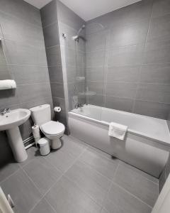 a bathroom with a toilet and a tub and a sink at Garland Modern 2 Bedroom Apartment With Parking London in Plumstead