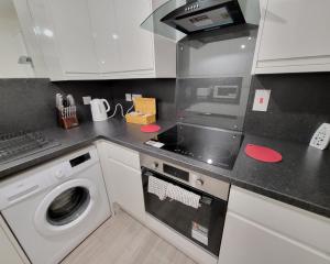 a kitchen with a stove and a washing machine at Garland Modern 2 Bedroom Apartment With Parking London in Plumstead