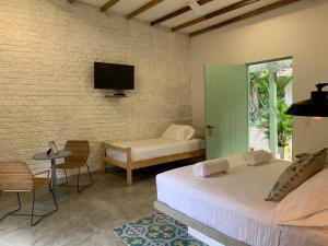 a bedroom with two beds and a tv on a brick wall at Waka Hotel Rural in Honda