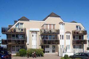 een groot gebouw met balkons en auto's geparkeerd op een parkeerplaats bij Ferienwohnung-48-mit-Meerblick-Residenz-Meeresbrandung-Duhnen in Cuxhaven