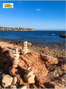 a pile of rocks sitting on a beach next to the ocean at Penthouse Naomi with two terraces, private solarium, sea view, swimming pool, with underground parking, pets allowed in Orihuela Costa