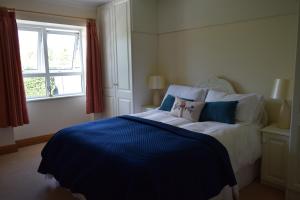 a bedroom with a large bed with a blue blanket at Teach Kitty Con in Dungloe