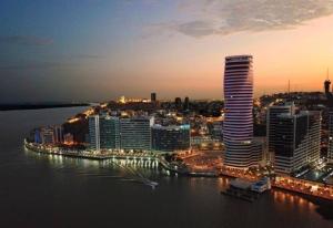 una vista de la ciudad por la noche con un edificio alto en Suite exclusiva con balcón y maravillosa vista en Guayaquil