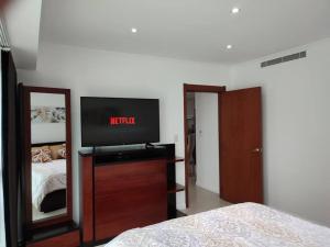 Dormitorio con cama y tocador con TV en Suite exclusiva con balcón y maravillosa vista, en Guayaquil