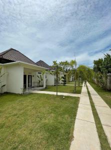 a white house with a grass yard and a sidewalk at Anchor Bed & Bread in Kuta Lombok