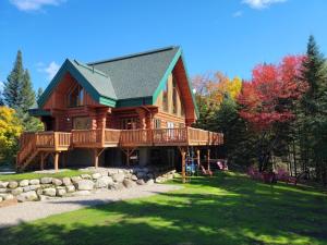 a large wooden house with a large deck at TREMBLANT Accès LAC et rivière SPA BILLARD FOYER Jaccuzi fireplace pool table lake and river access in Lac-Superieur