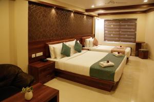 ein Schlafzimmer mit zwei Betten und einem Sofa darin in der Unterkunft Hotel Crystals Cove in Thekkady