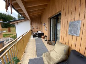 a porch of a house with a couch on a balcony at Moderne Kaminstube in Ramsau am Dachstein