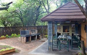 eine Terrasse mit einem Grill, einem Tisch und Stühlen in der Unterkunft Marloth Park Hippo House in Marloth Park
