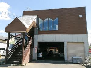 ein Gebäude mit einer Garage mit einem Auto darin in der Unterkunft Guesthouse ushiyado in Naka-shibetsu
