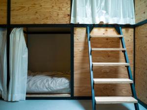 a bunk bed with a ladder next to a bed at Guesthouse ushiyado in Naka-shibetsu