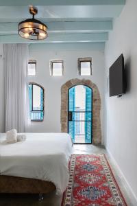 a bedroom with a large bed and a flat screen tv at Daya - Old City Acre in Acre