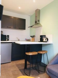 a kitchen with a counter and two stools at Grand Studio avec terrasse proche de l'hypercentre de Lorient in Lorient