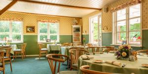 a dining room with tables and chairs and windows at Bromølle Kro in Jyderup