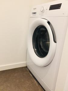 Un lave-linge blanc est installé dans une pièce. dans l'établissement Grand Studio avec terrasse proche de l'hypercentre de Lorient, à Lorient