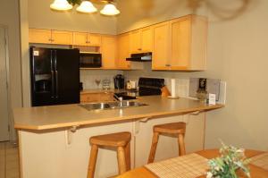 een keuken met een spoelbak en een zwarte koelkast bij Apartment 405 Bear Creek Crossing in Canmore