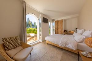 a bedroom with a bed and a chair and a window at Moulin de la Roque in Althen-des-Paluds