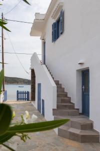 a white house with blue doors and stairs next to the water at Aerides Boutique Rooms in Vathi