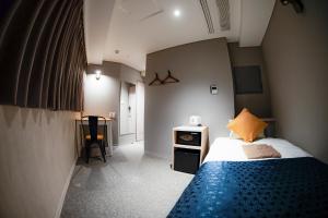a small bedroom with a bed and a table at Hotel S-Presso North in Osaka