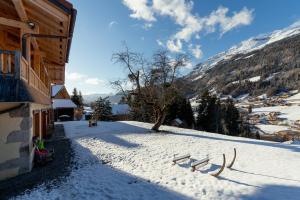 un patio cubierto de nieve con un edificio y una montaña en Les Picaillons - Le Chalet, en Les Villards-sur-Thônes