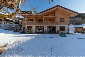 una casa de madera en la nieve con entrada en Les Picaillons - Le Chalet en Les Villards-sur-Thônes