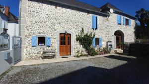 una casa in pietra bianca con persiane blu e una porta di Meublé de tourisme au cœur du village à Aramits , haut Béarn ad Aramits