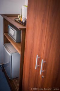 a wooden cabinet with a microwave in a room at Central Beach Inn in Mirissa
