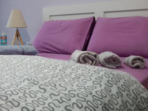 Una cama con almohadas moradas y toallas. en Feels Like Home 2, en Atenas