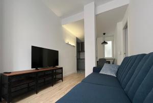 een woonkamer met een blauwe bank en een flatscreen-tv bij MGG - Apartamento Muelle in Albacete