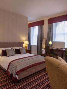 a large bedroom with a large bed and a desk at Eskdale Hotel in Langholm