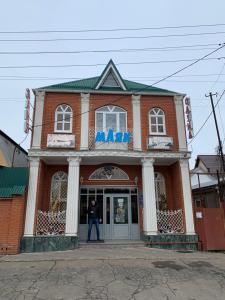 クラスノダールにあるГостевой дом "Маяк"の煉瓦造りの建物の出入り口に立つ男