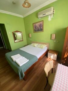 zieloną sypialnię z łóżkiem i lustrem w obiekcie Camel Hotel & Apart w mieście Antalya