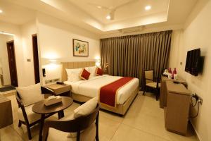 AttingalにあるSooryaのベッド、テーブル、椅子が備わるホテルルームです。