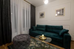 a living room with a green couch and a glass table at Apartman Park in Bijeljina