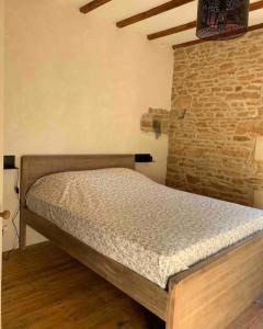 Cama en habitación con pared de ladrillo en Au p’tit bonheur d’Augé, en Augé