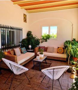 un patio con 2 sillas, un sofá y mesas en Casa Rural Mirador del Sol, en Villalba del Alcor