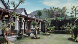 a house with palm trees in front of it at The Lava Bali Villa and Hot Spring in Kintamani