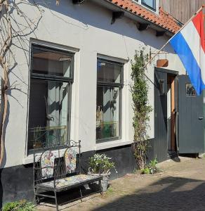 a bench sitting outside of a house with a flag at B&B In den Wijde Koe in Maassluis