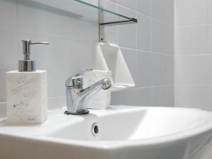 La salle de bains est pourvue d'un lavabo, d'un robinet et de serviettes en papier. dans l'établissement Feels Like Home 2, à Athènes